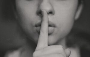 imagem de senhora a fazer o gesto de silêncio com o dedo indicador em frente à boca
