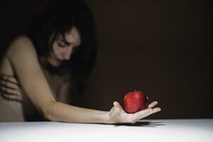 imagem de senhora de mão aberta com uma maçã vermelha na mão